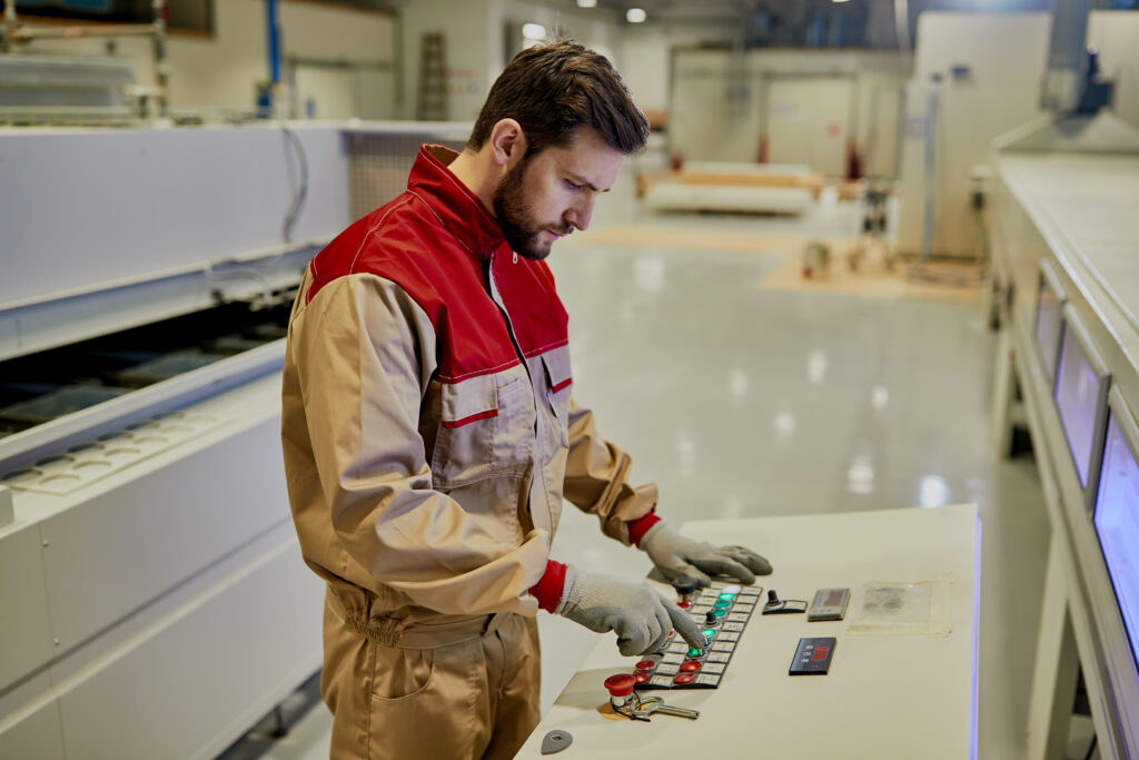 male worker using automated machine while working at woodworking