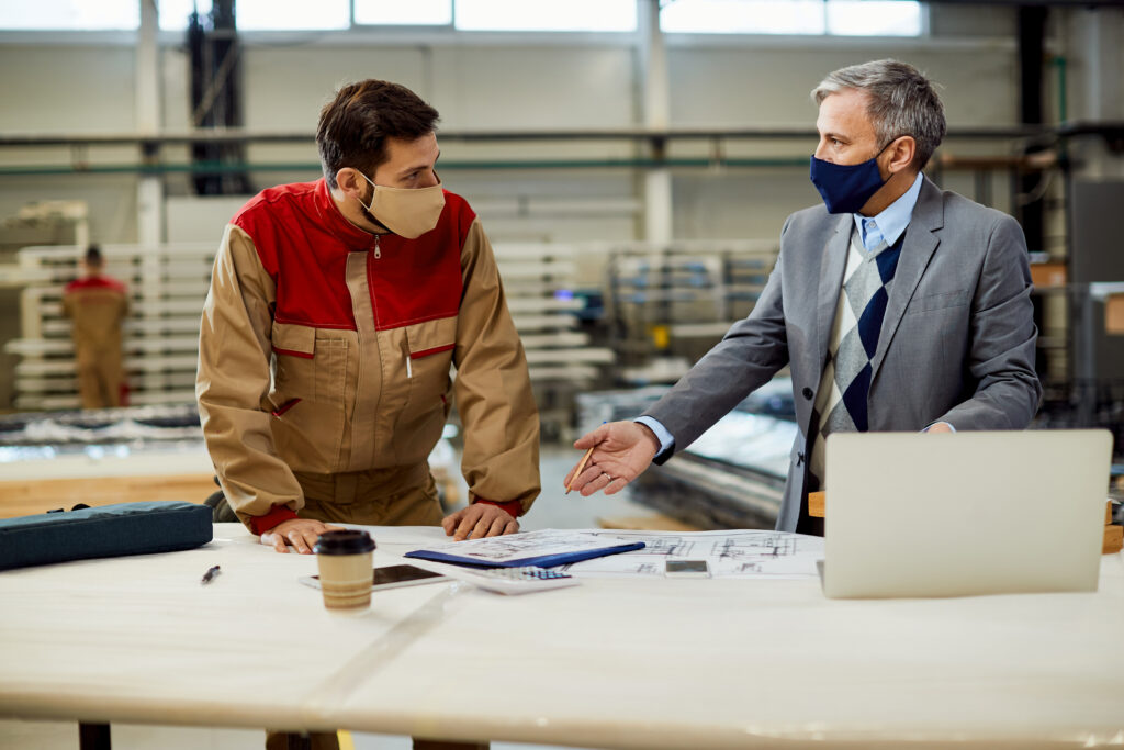 project manager talking to carpenter while examining blueprints